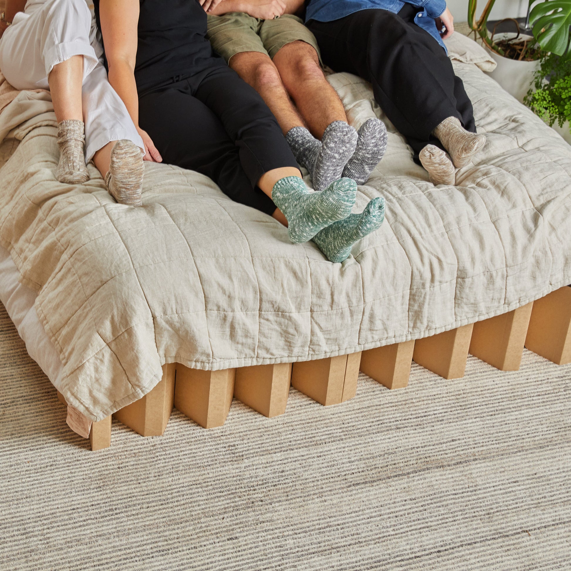 Yona Cardboard Bed in natural finish viewed from the front with 4 people on the bed