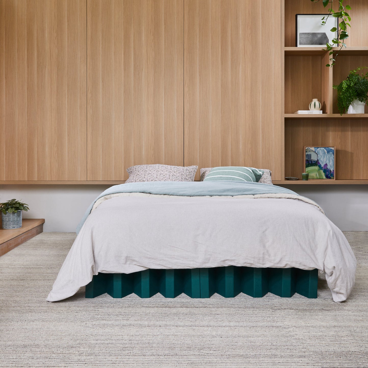 Yona Cardboard Bed in forest green finish styled with neutral bedding and built-in wood shelving